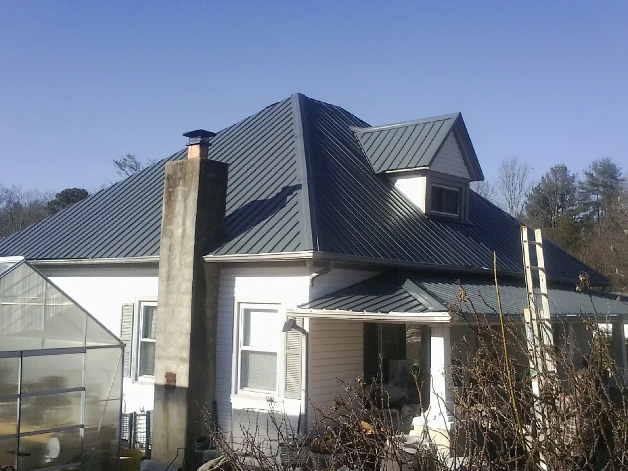 Dark blue standing seam metal roof on a white farmhouse with dormer — Slate & Tile Roof Repair by Roofing Brothers in Rolling Meadows