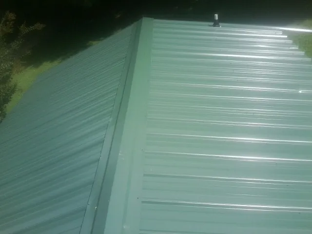 New green metal panels meeting at the ridge of a roof — Flat Roof Repair work by our crew in Rolling Meadows