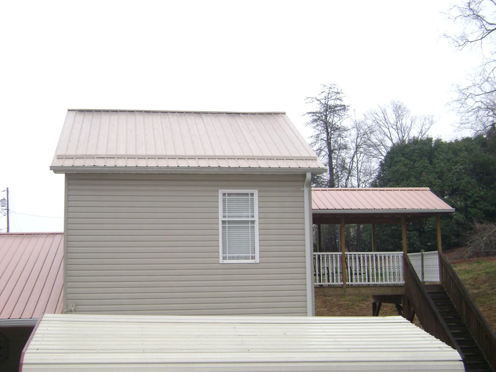 Tan metal roofs on a two story addition and attached porch, from a Roof Replacement job in Rolling Meadows