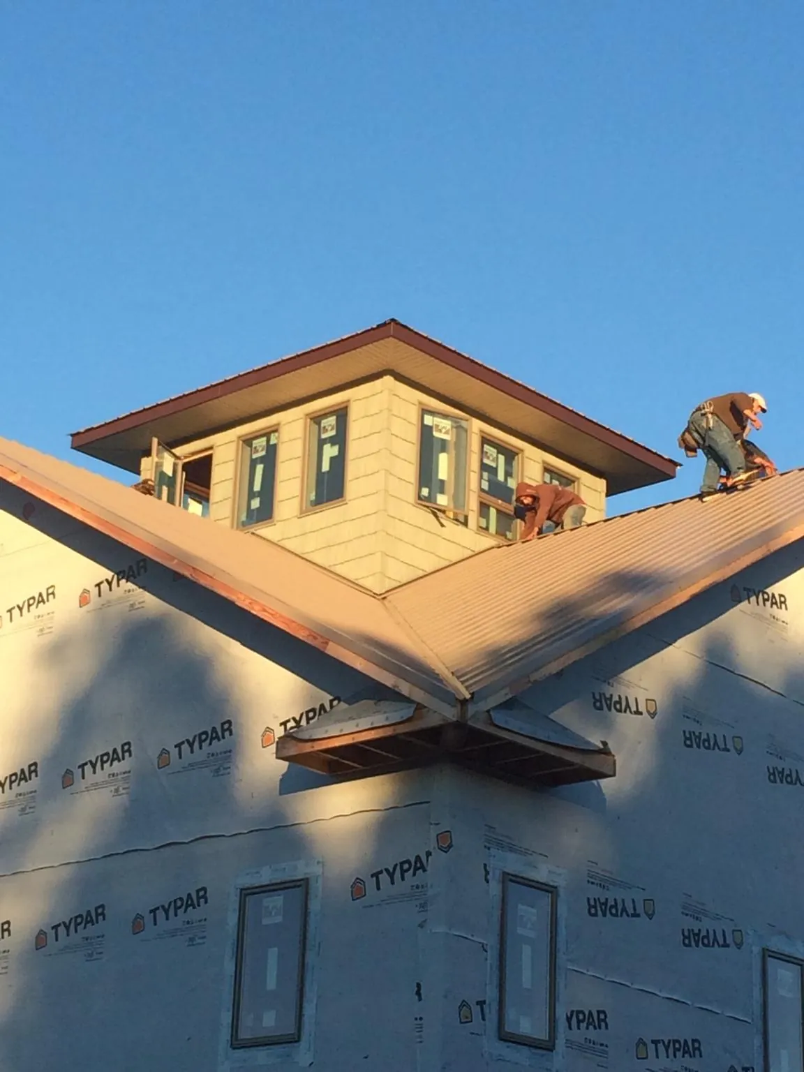 Roofers working around a rooftop cupola on a new metal roof at sunset — Roof Waterproofing in Rolling Meadows by Roofing Brothers